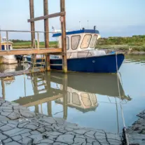 Bateau bleu amarré près d’un quai en bois