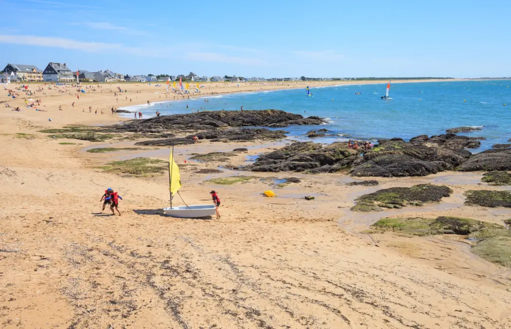 Plage animée avec rochers et voiliers colorés