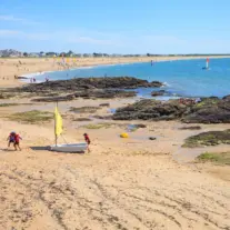 Plage animée avec rochers et voiliers colorés