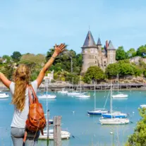 Woman overlooking harbor with sailboats and castle