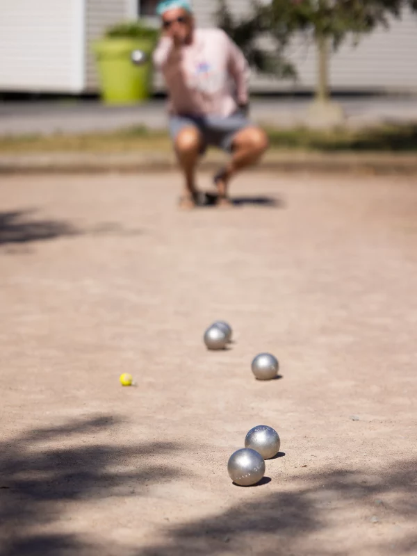 Boules de pétanque sur terrain avec joueur accroupi