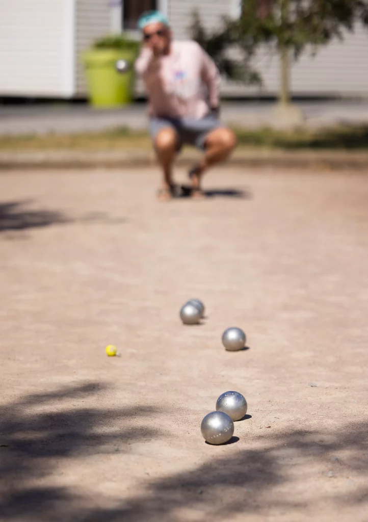 Boules de pétanque sur terrain avec joueur accroupi