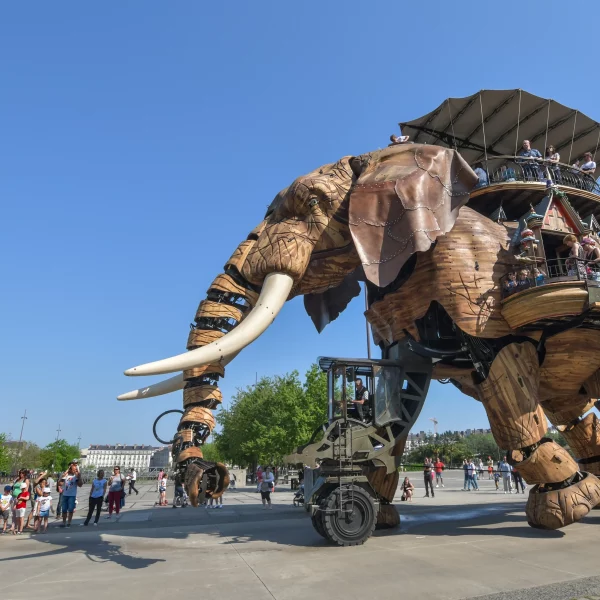 Éléphant mécanique géant transportant des visiteurs en ville