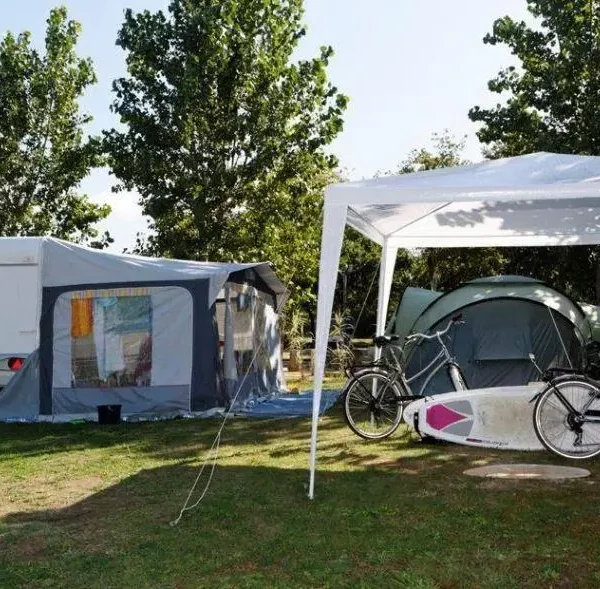 Camping avec caravane, tente et vélos sous auvent