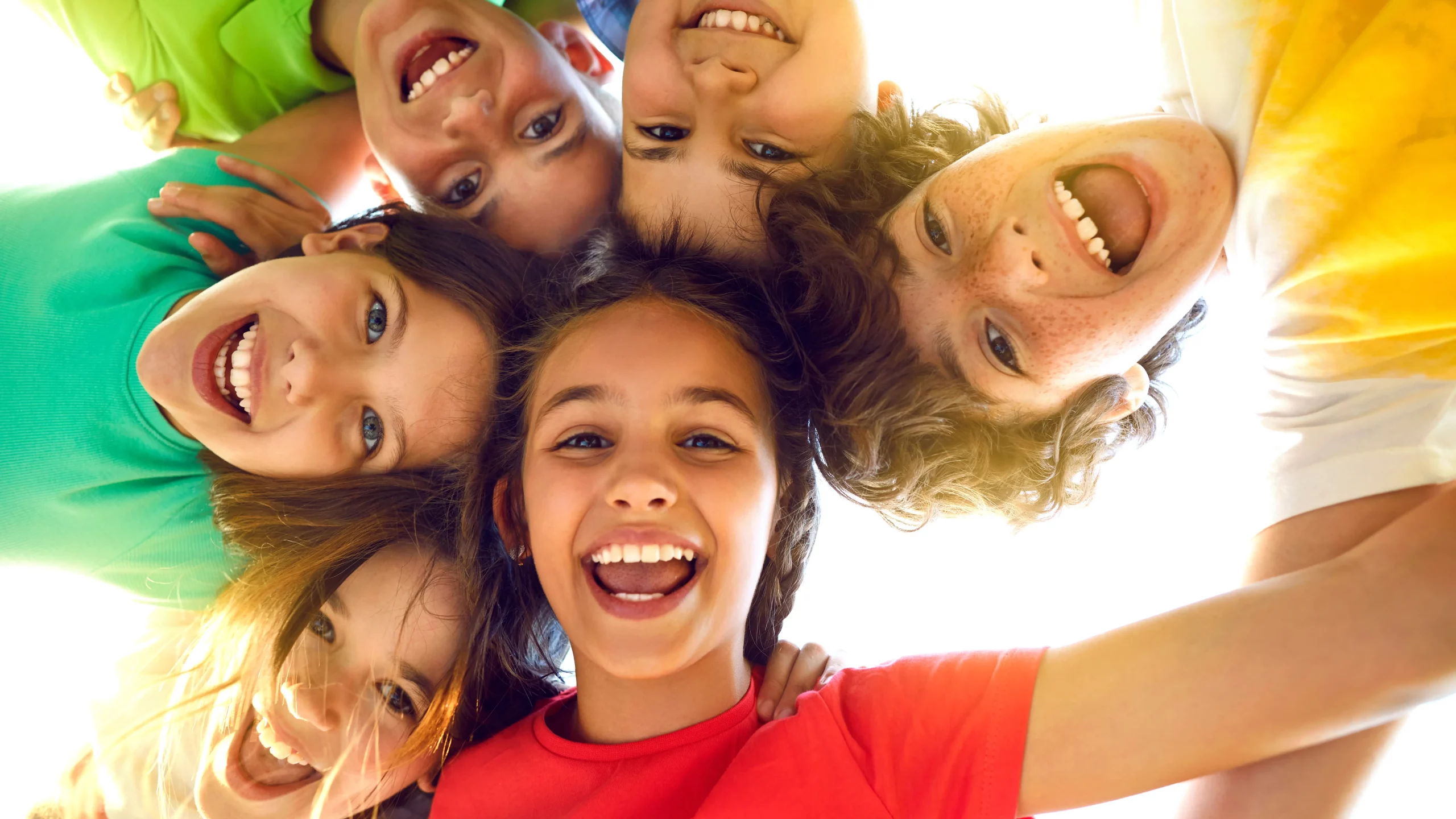Six smiling children taking a selfie together outdoors