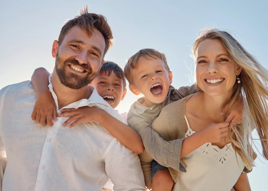 Smiling family of four outdoors in sunlight