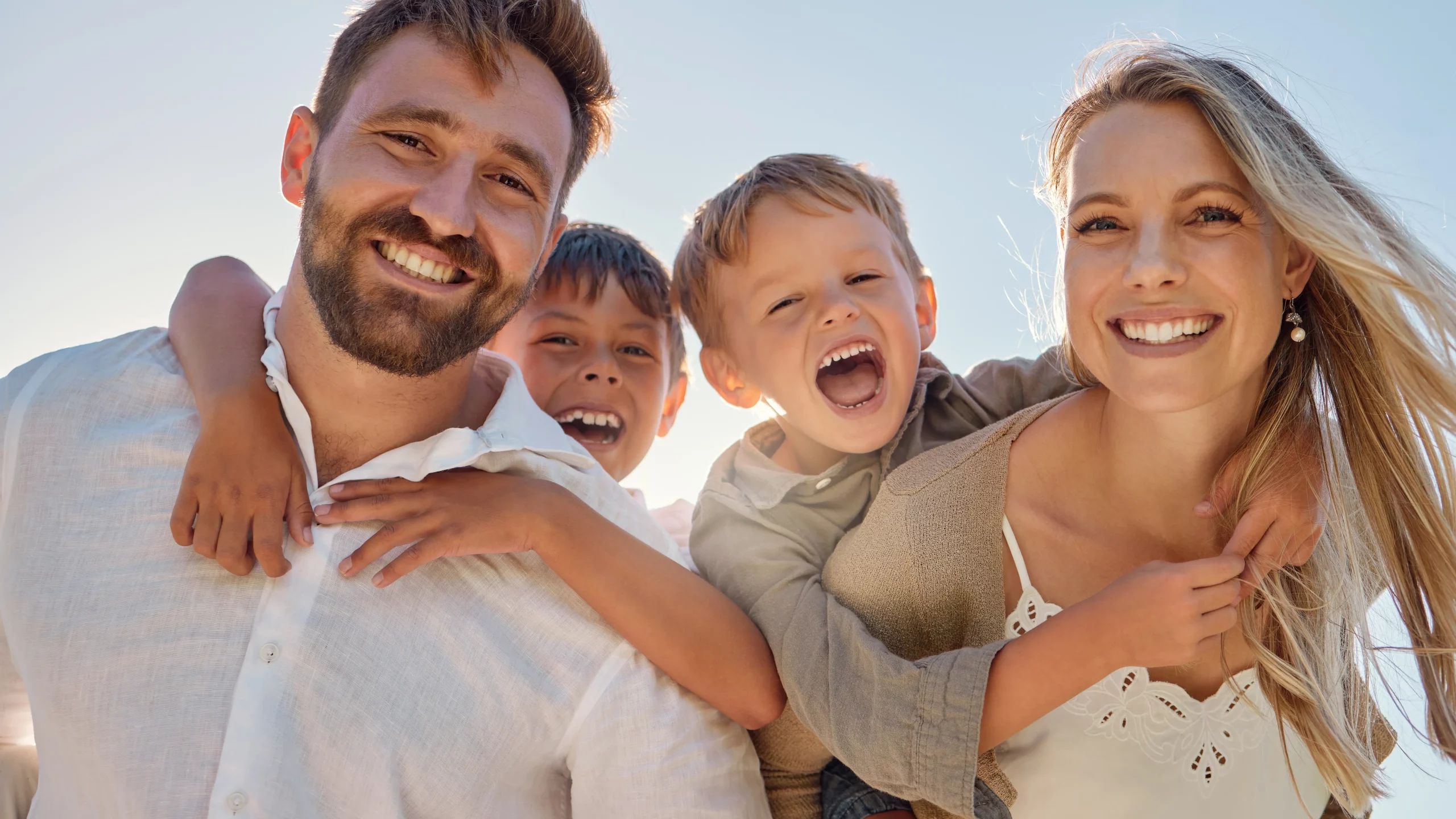 Smiling family of four outdoors in sunlight