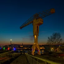 Grande grue industrielle illuminée au bord de rivière