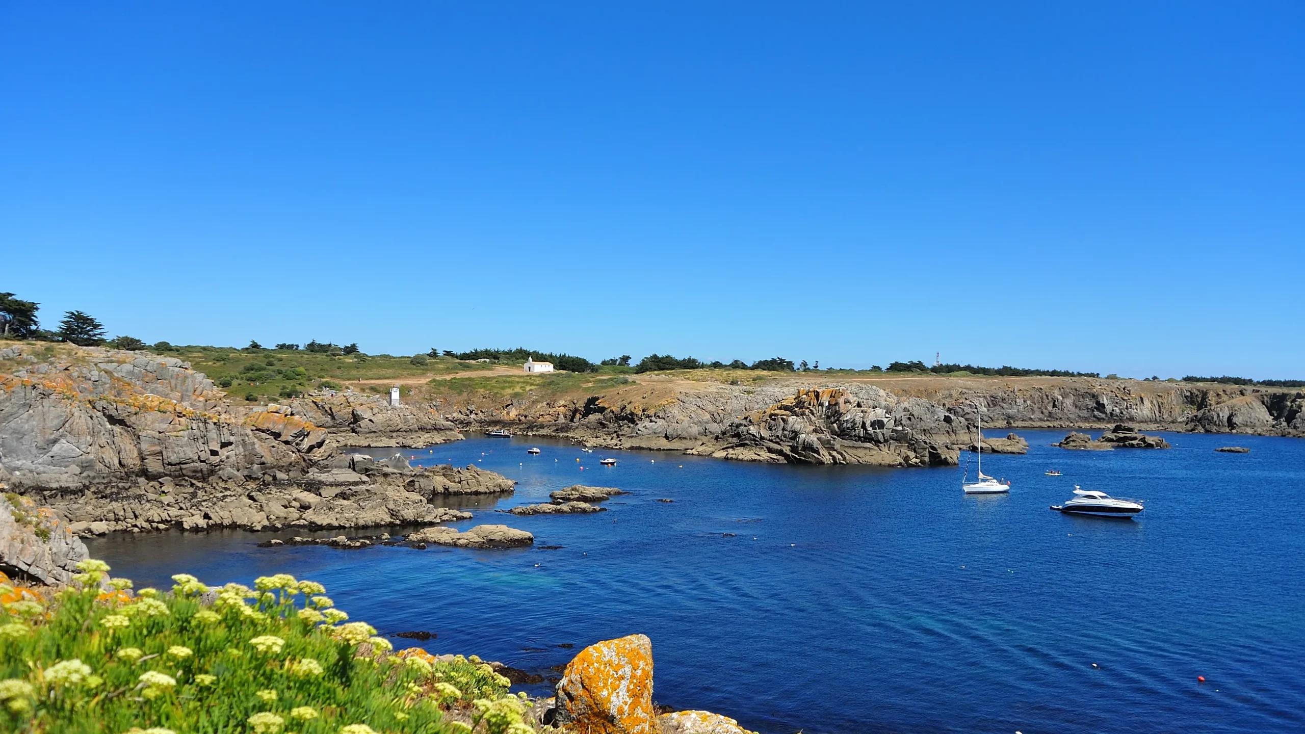 Crique rocheuse aux eaux bleues et voiliers