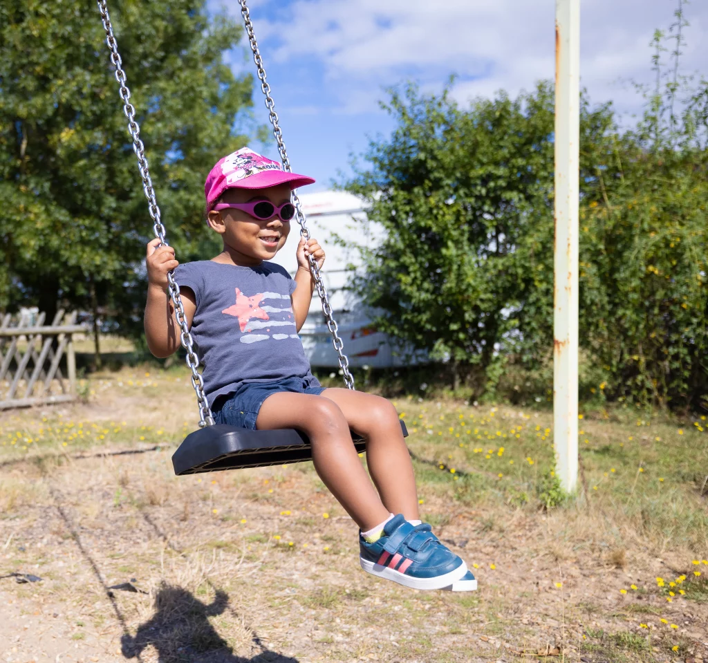 Enfant souriant sur une balançoire au parc