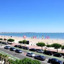 Plage animée avec voiliers colorés et promenade urbaine