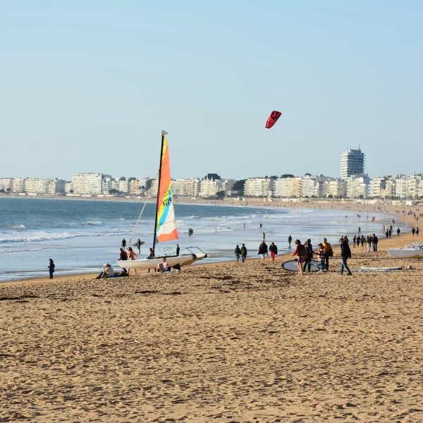 Plage animée avec voiliers et immeubles côtiers