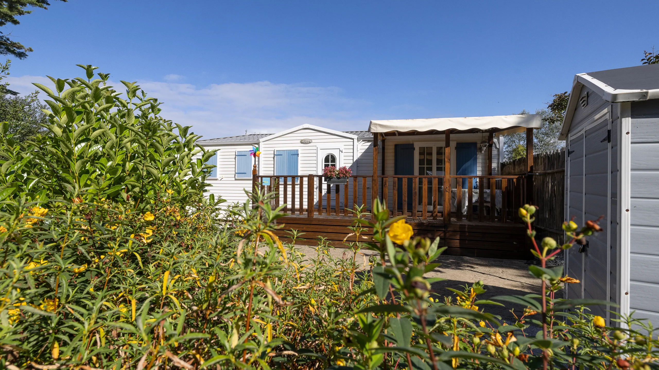 Mobil-home avec terrasse en bois et jardin fleuri