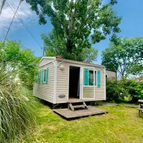 Mobil-home beige avec volets verts en camping