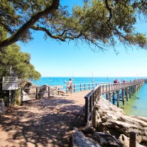 Jetée en bois sur mer turquoise et voiliers