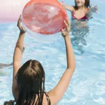 Children playing with beach ball in swimming pool