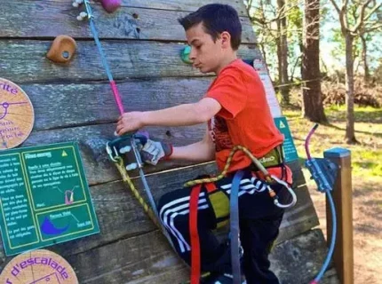Garçon grimpant un mur d’escalade extérieur sécurisé
