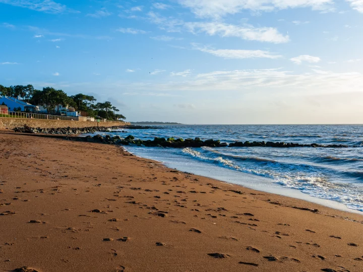 Plage sableuse avec vagues et maisons côtières