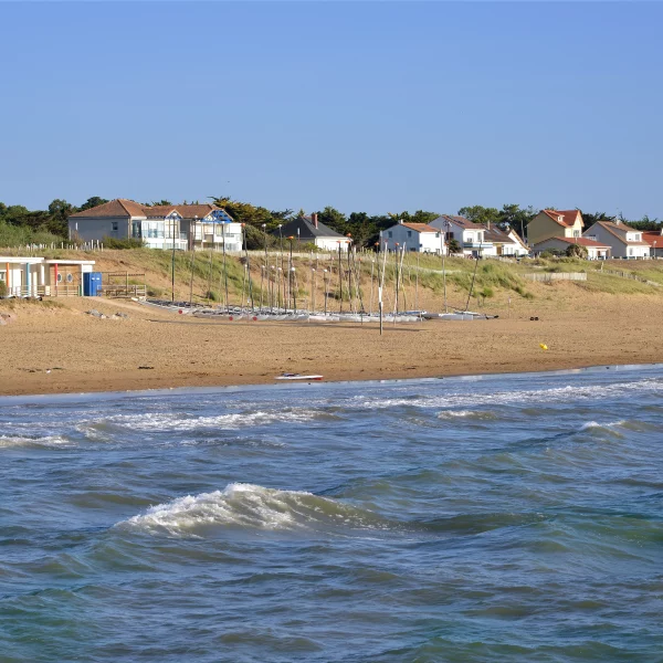 Plage avec voiliers et maisons en bord de mer
