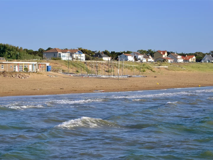 Plage avec voiliers et maisons en bord de mer