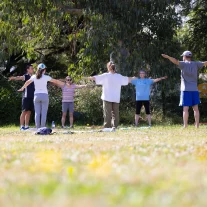 Groupe faisant exercices bras écartés dans un parc