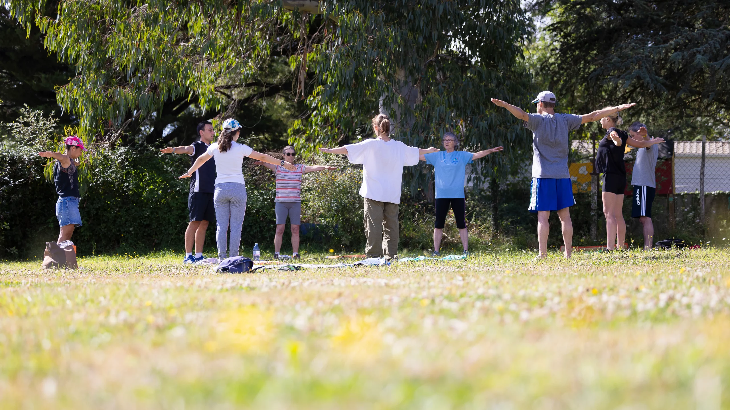 Groupe faisant exercices bras écartés dans un parc